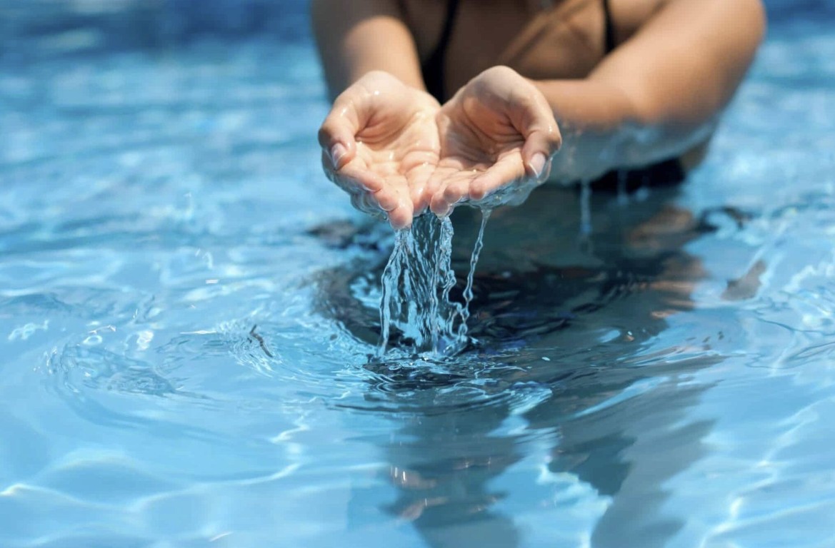 Crystal clear pool water cupped in hands